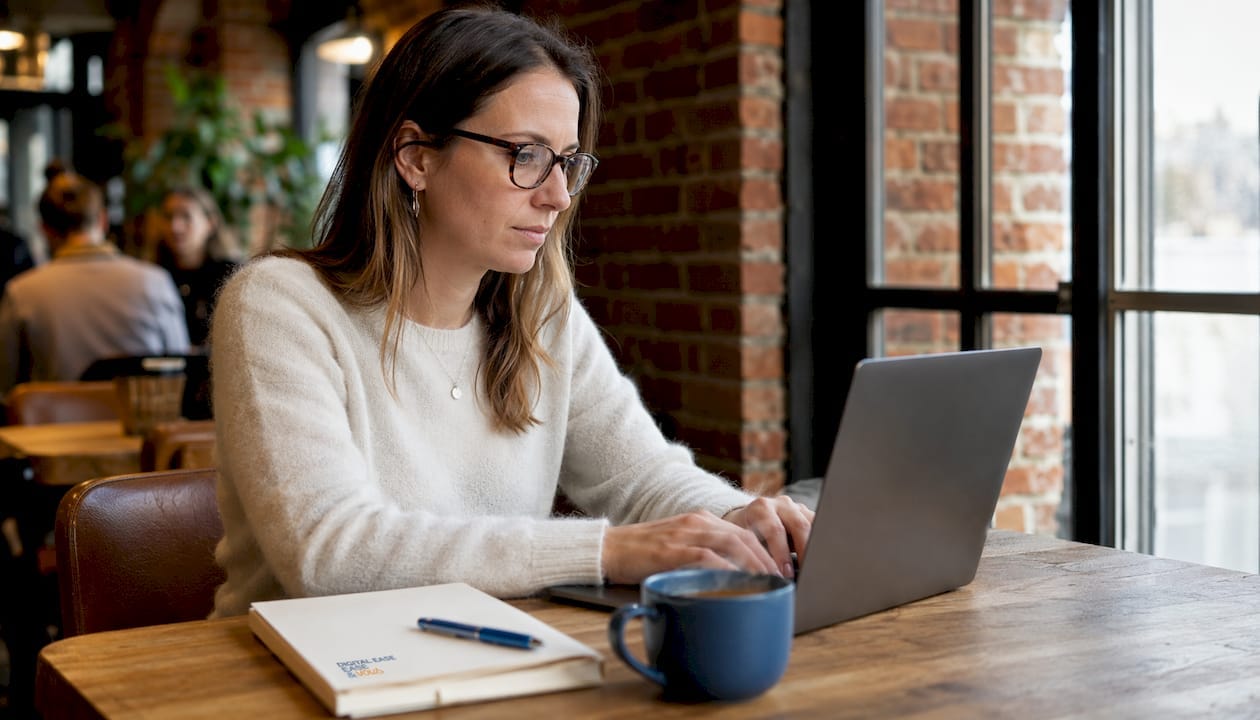 Une cheffe d'entreprise gère son activité depuis son ordinateur, installée à un bureau épuré.