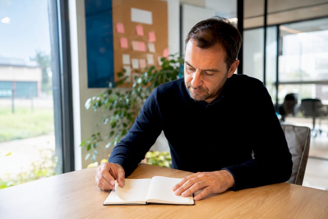 Proposition de valeur PME : la formuler et la tester vite 3 Chef d'entreprise PME tenant un stylo au-dessus d'un carnet blanc